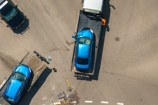 Tow truck hauling smashed vehicle on car accident site.